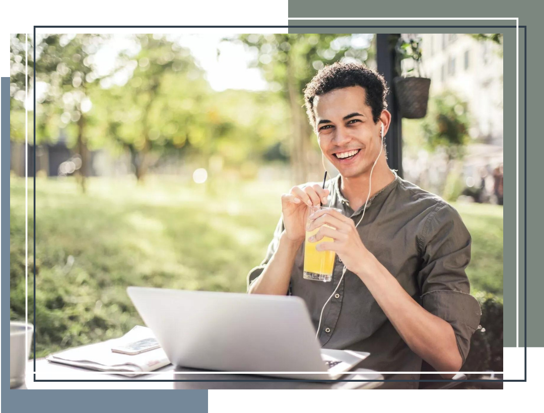 Young-man-drinking-juice-outside-with-laptop