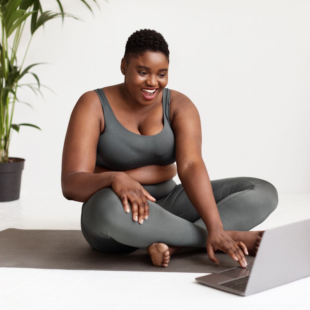 A happy woman looking at her computer after a yoga session